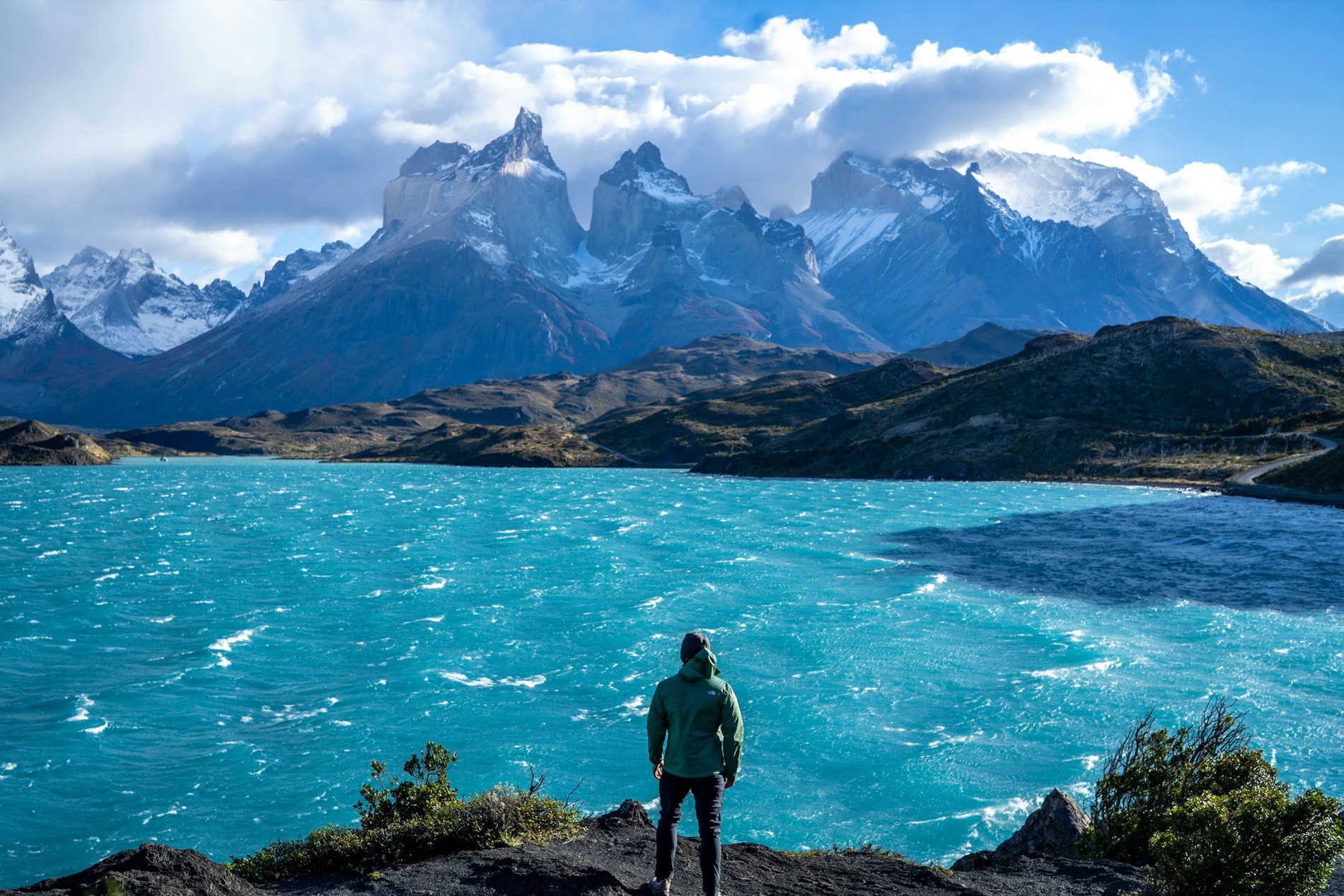 Fotógrafo de pie en la cima de una montaña junto a un lago patagónico